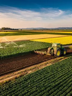 Vast green agricultural field with a tractor, symbolizing the 2026 Farm Bill's impact on farming.