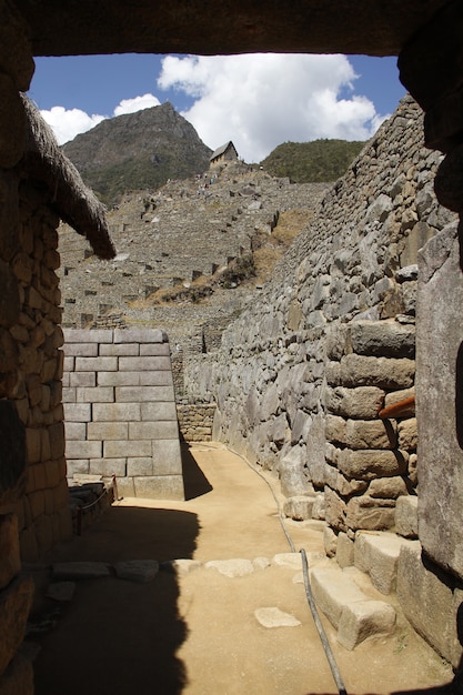 A view of the Ollantaytambo Fortress, with its massive terraces and intricate stonework. The town of Ollantaytambo is visible in the foreground, with traditional adobe houses and cobblestone streets.