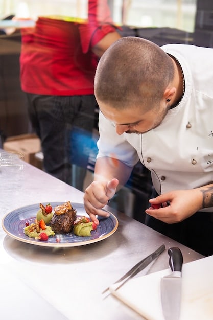 A Peruvian-American chef presenting a beautifully plated traditional Peruvian dish in a modern restaurant setting. The focus is on the vibrant colors of the food and the chef's pride in their heritage.